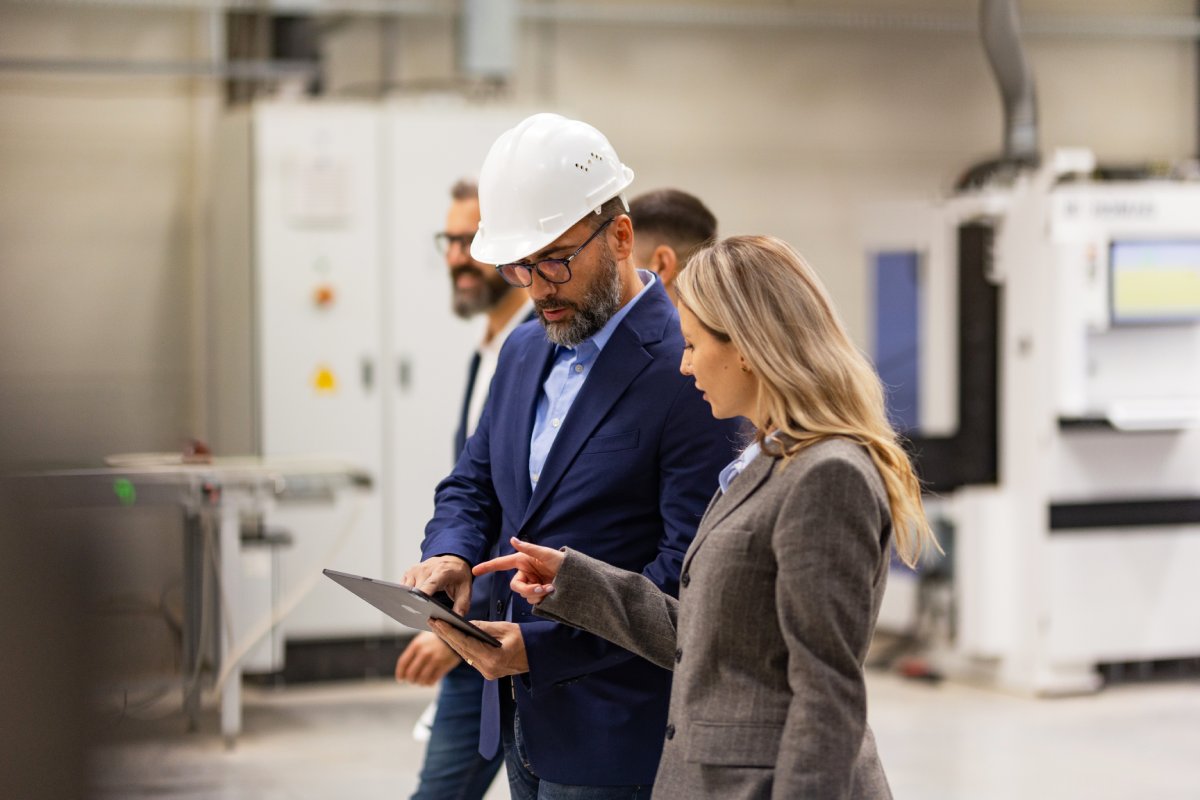 Engineer, foreman consulting with director in modern industrial factory, talking about new production project or investment. Team management in manufacturing facility.
